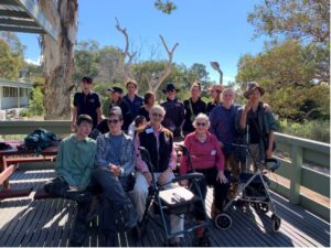 A group of people sitting on a deck with gum trees behind them.
