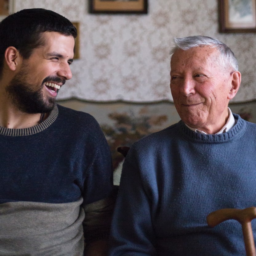 Two people smiling and laughing at each other while sitting on a couch