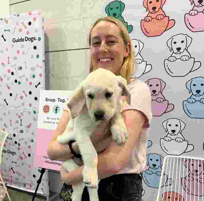 A person holding a yellow Labrador puppy at the Guide Dog Cafe