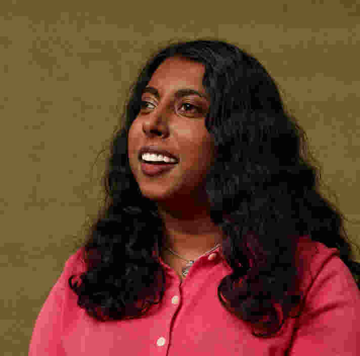 Guide Dogs Client Abi looking away from the camera, smiling, against a beige coloured background.