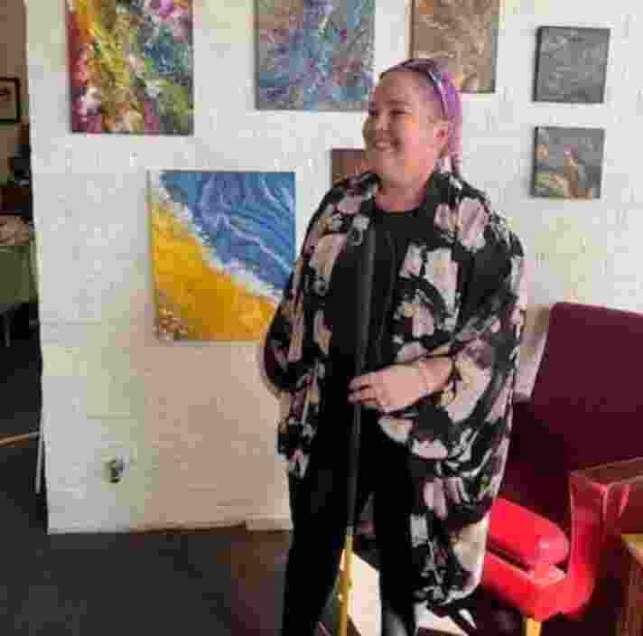 Leah standing in front of artworks on a wall