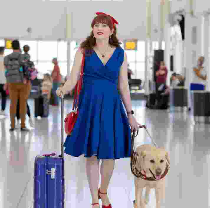 A person walking with their yellow Guide Dog through the airport