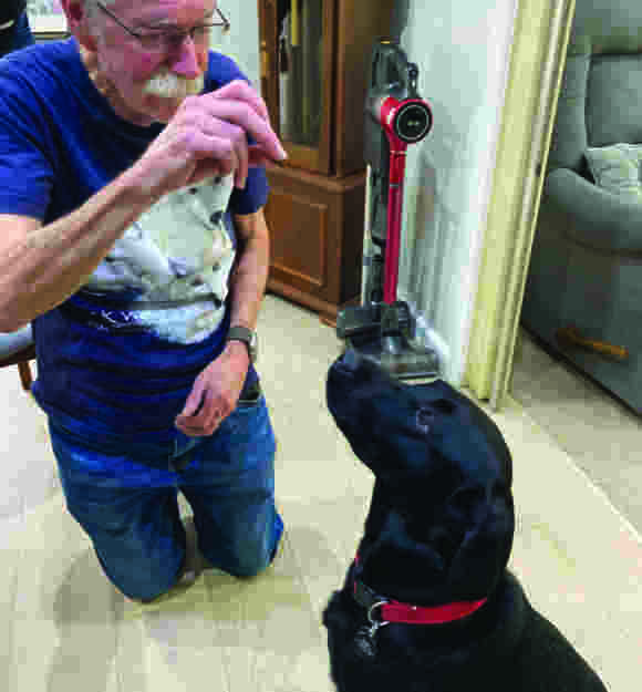 Eugene holding a treat for black Labrador Gene.