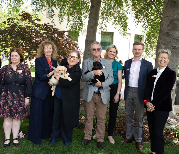 NSW Board members standing outside. Two are holding puppies.