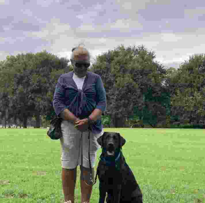 Puppy Raiser standing next to a black Labrador.