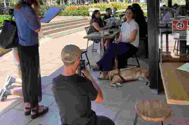 People filming a Client with a Guide Dog at a cafe.