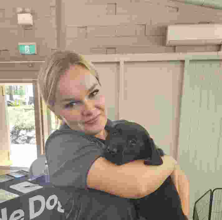 Emma holding a black Labrador puppy.