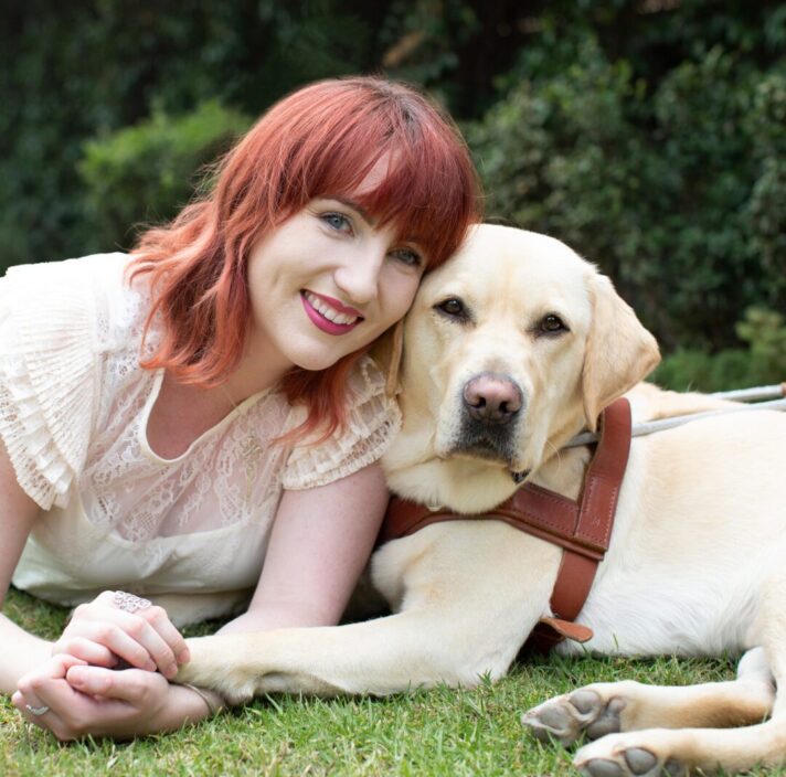 A person and her yellow Labrador Guide Dog laying down.