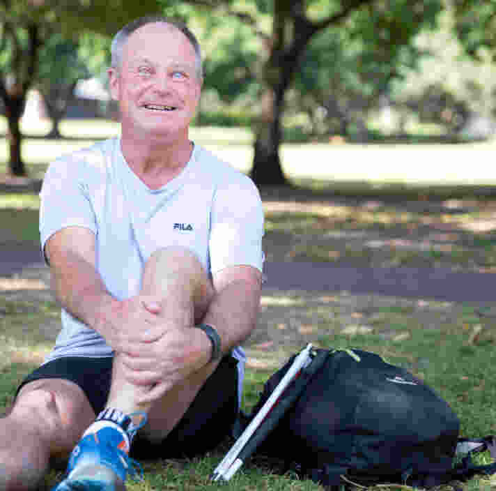 A person sitting in a park next to a cane.