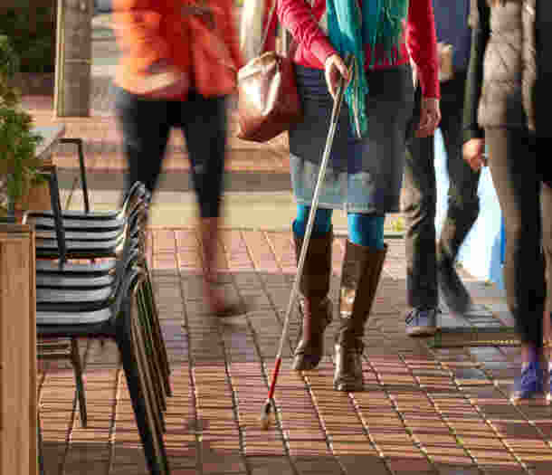 A person walking down the street using a cane.