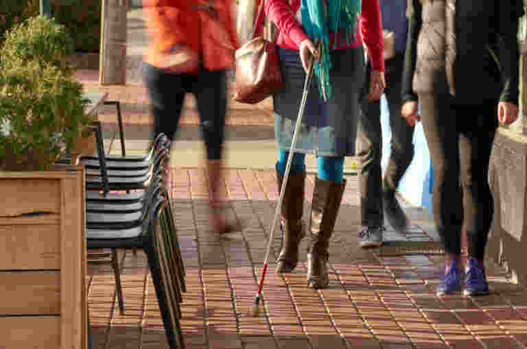 A person walking down the street using a cane.