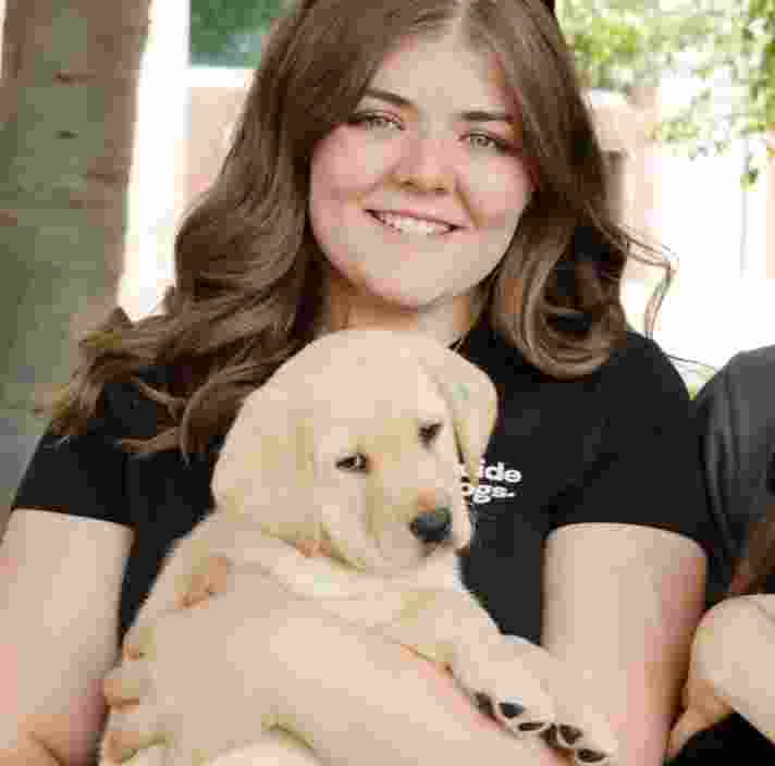 Maddy holding a yellow Labrador puppy.