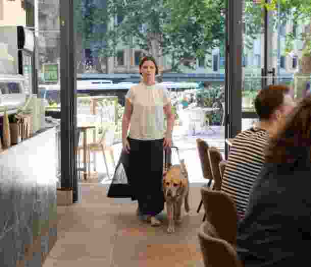 Sarah Hirst walking through a cafe with her Guide Dog.