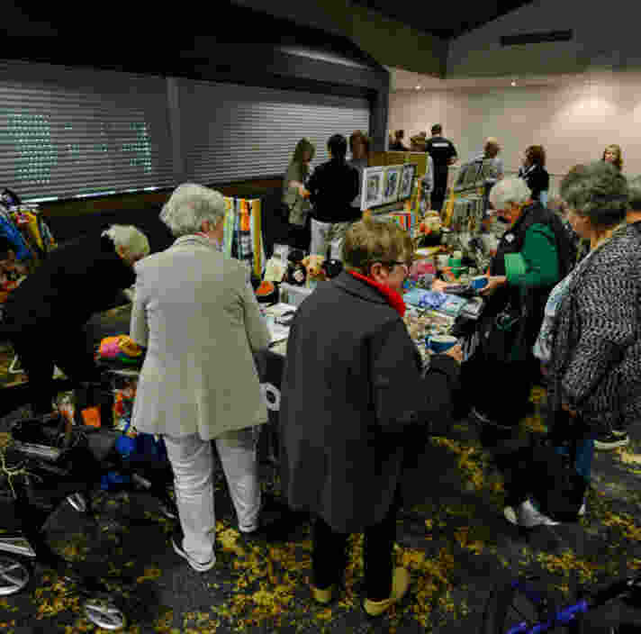 People stand around a table full of Guide Dogs merchandise.