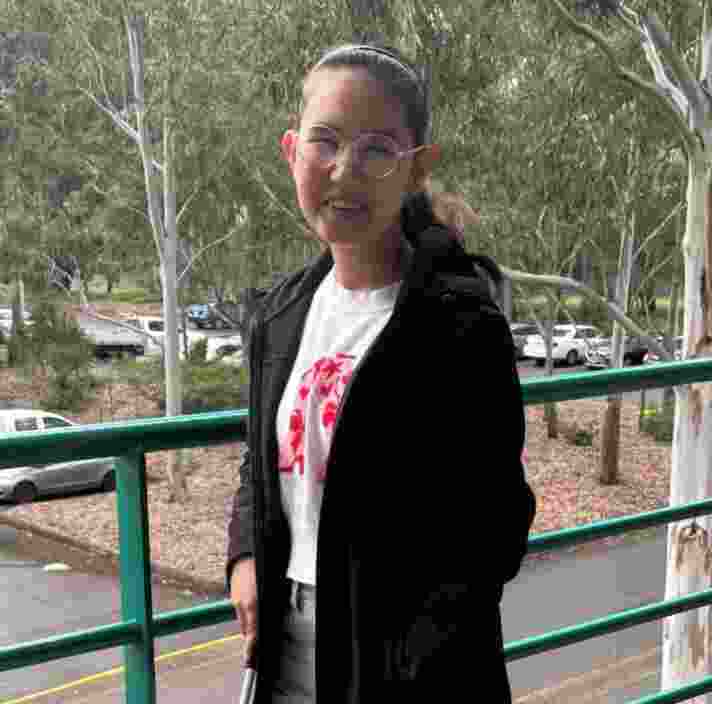 A young woman standing on a balcony with a white cane.