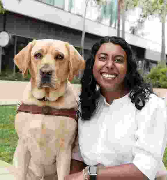 Abby sitting next to her yellow Guide Dog Duke.