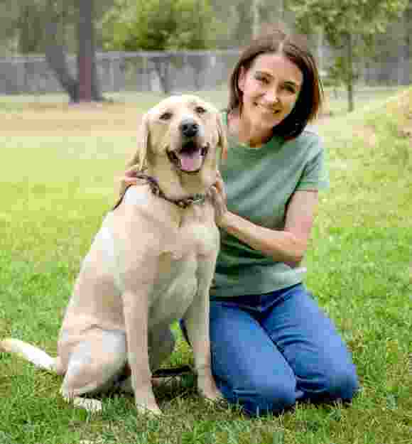 Dr Katrina sitting next to a yellow Labrador.
