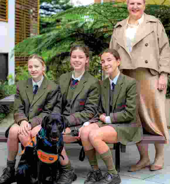 Allysia standing with three students and black Labrador Abbie.