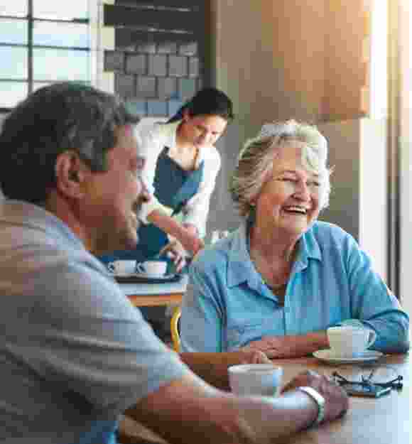 A group of people sitting at a cafe smiling.