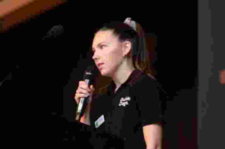 Karlee Symonds presenting in front of school kids in an auditorium.