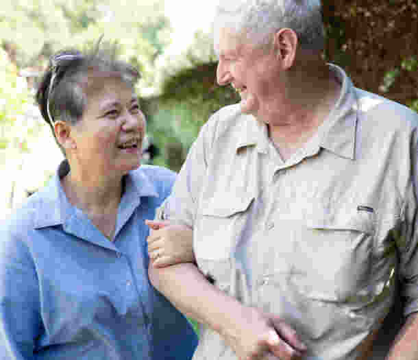 Two people walking arm in arm and smiling.