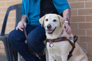 A Handler sitting next to his Guide Dog.