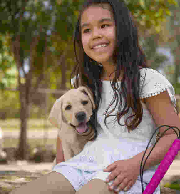Sora sitting with a yellow Labrador puppy.
