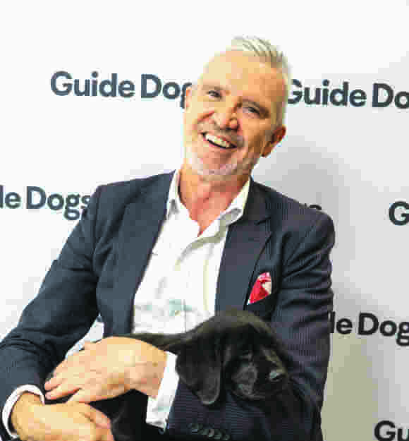 Dale Cleaver smiling at the camera holding a puppy.