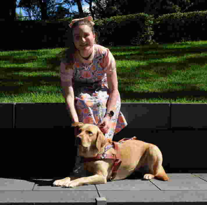 Charlotte sitting outside with yellow Labrador Guide Dog Holly