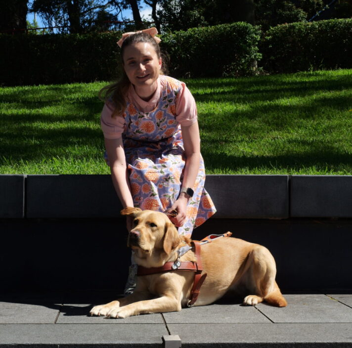 Charlotte sitting outside with yellow Labrador Guide Dog Holly
