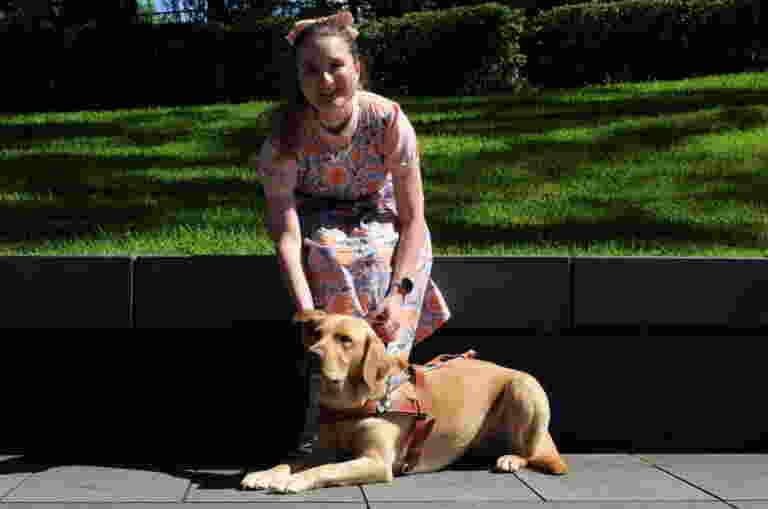 Charlotte sitting outside with yellow Labrador Guide Dog Holly
