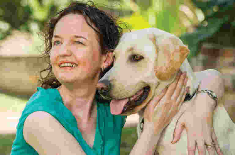 A woman hugs her Guide Dog affectionately.