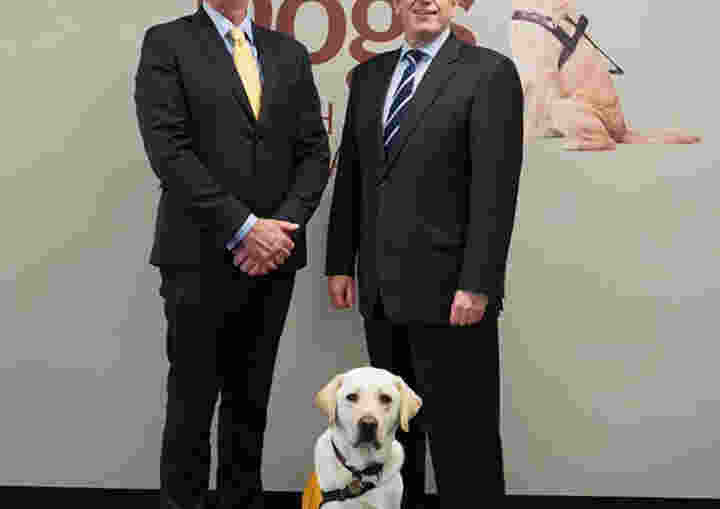 John Oliver and Joe Thorp standing in front of a Yellow Labrador