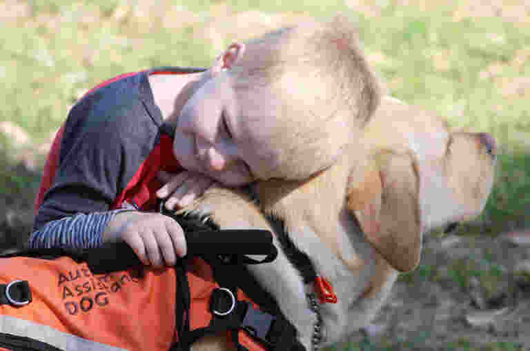 A young child hugging an Autism Assistance Dog