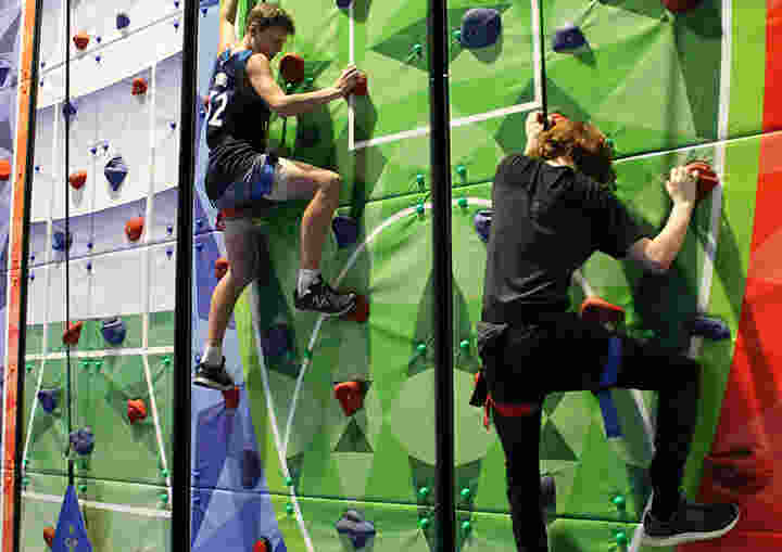 Two Life Camp participants climbing a green rock wall