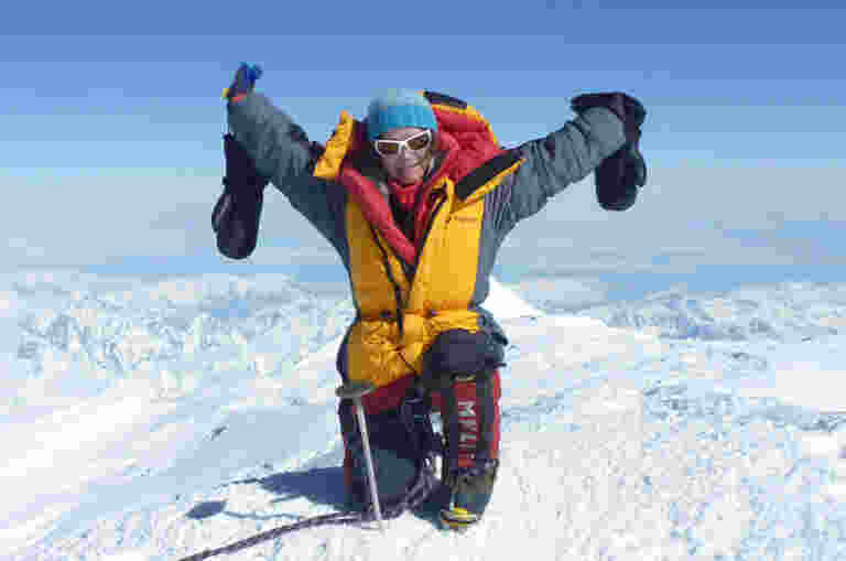 Guide Dogs Board member Katie Sarah posing with her arms up at the top of Mount Denali.