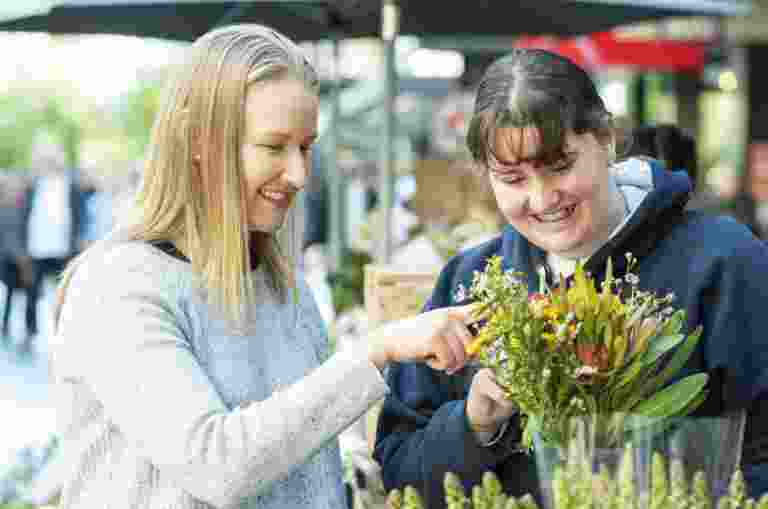 Two people looking at fresh flowers at a flower shop. They both have smiles on their faces.