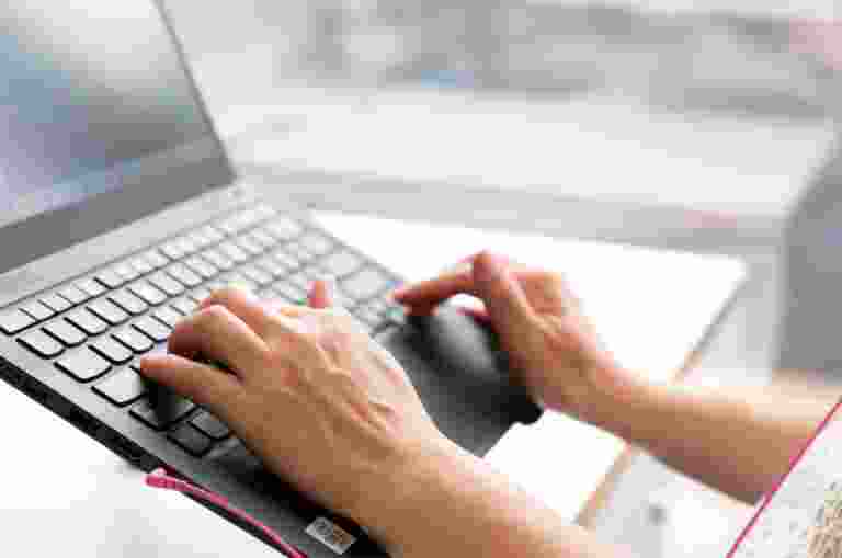 Person's hand using the keyboard of a laptop.