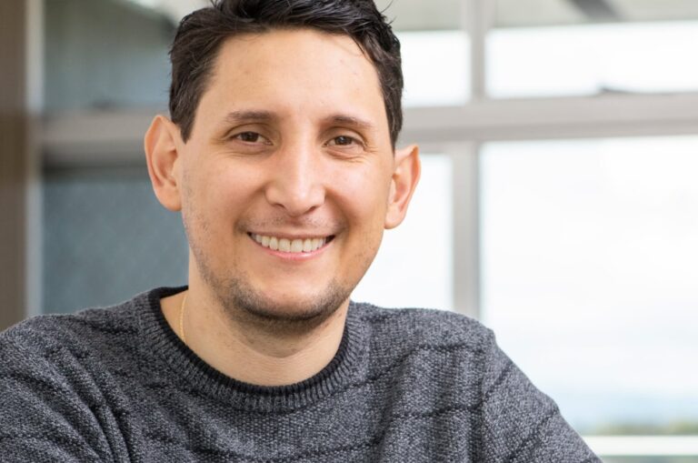 A close up of a person at home smiling at the camera.