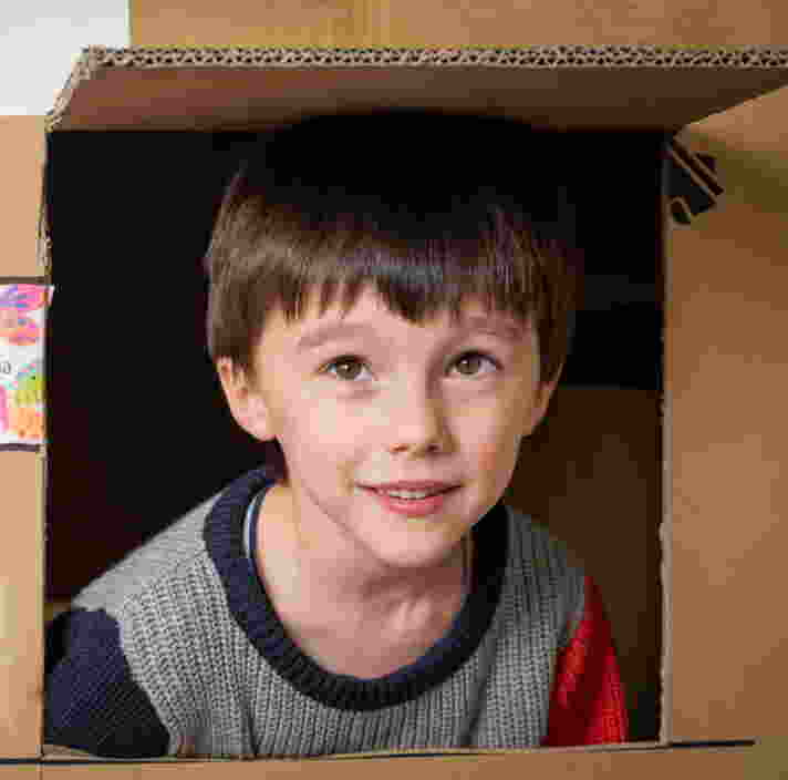 A young child sitting inside a cardbox and smiling
