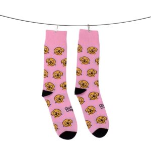 Two socks, adorned with yellow dog face patterns against a pink background, are hanging on a line secured by clothespins.