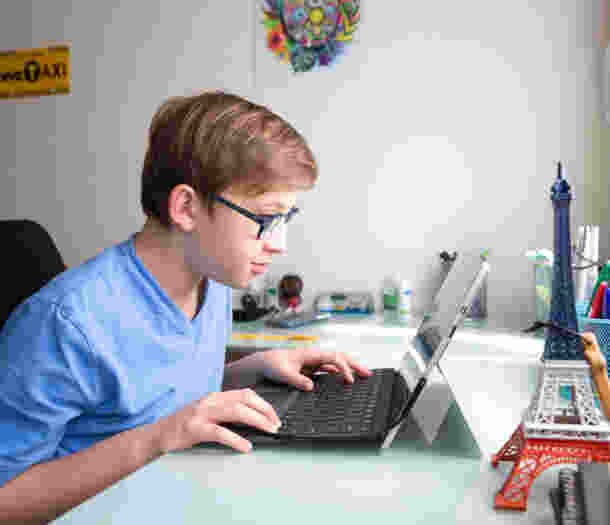 A young boy uses a laptop computer on a desk.