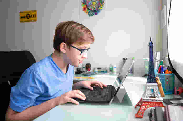 A young boy uses a laptop computer on a desk.