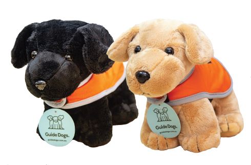Two Plush Dog - Standing toys, one black and one tan, each wearing an orange vest and a round Guide Dogs tag around its neck.