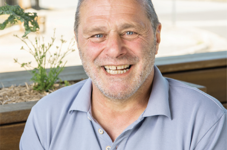 Man wearing a blue polo, smiling at the camera