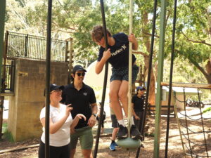 A photo of Jason Loh with another staff member assisting a young client on an adventure playground.