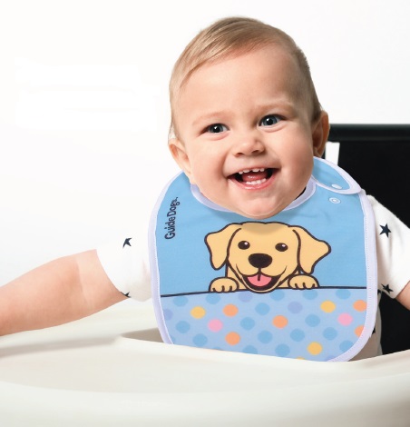 A smiling baby wearing a Baby Bib featuring a cartoon puppy design sits in a high chair.