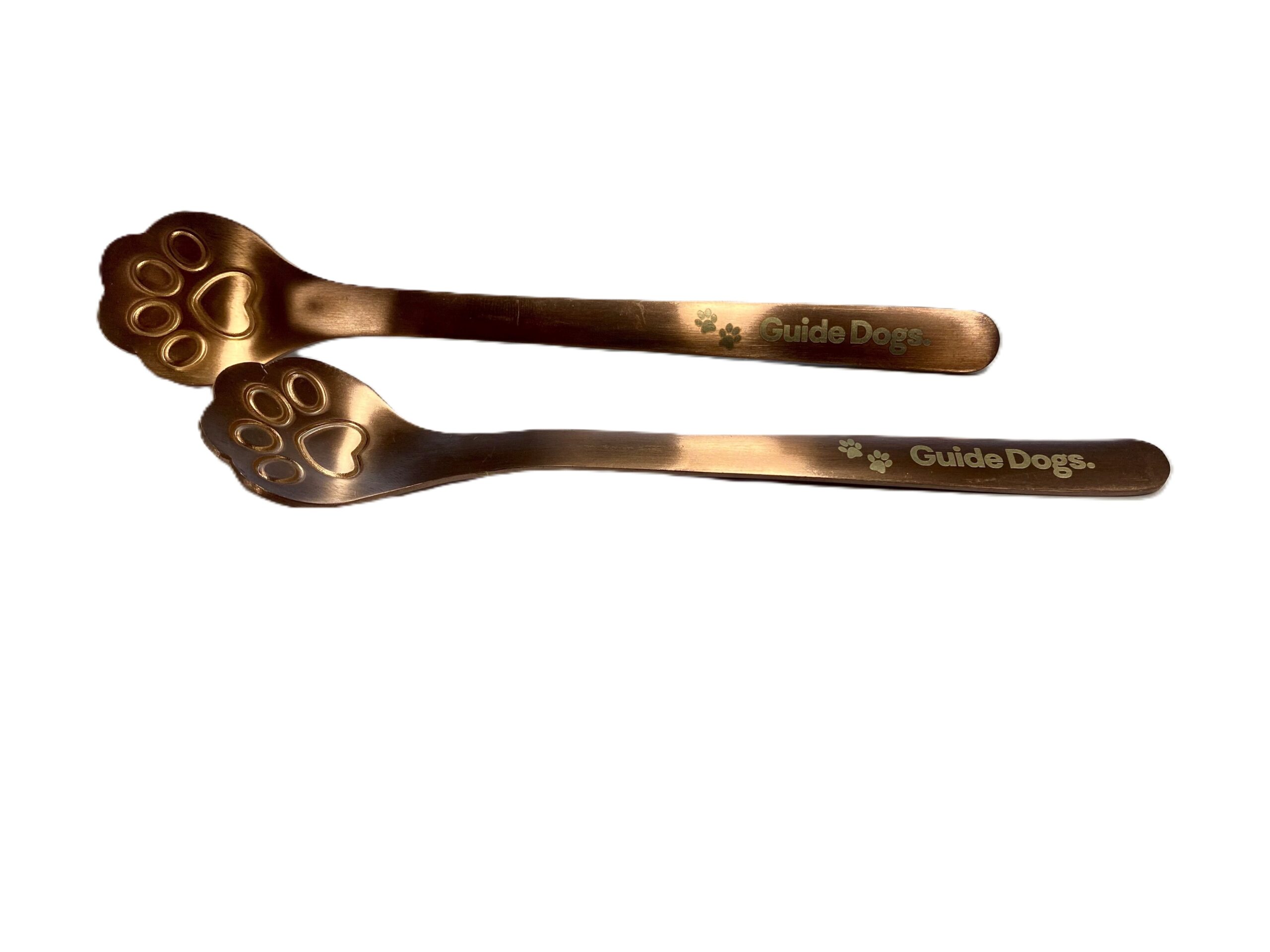 Two metallic Paw Print spoons, each with handles decorated with paw prints and the words Guide Dogs printed on them.