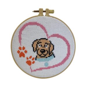 Introducing the "Cross Stitch" featuring an adorable puppy adorned with orange paw prints and a pink heart, elegantly framed in a wooden hoop.