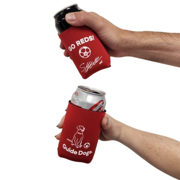 Two hands hold aluminum cans wrapped in AUFC Can Coolers, one can cooler reading Go Reds! with a signature and the other displaying a guide dog logo.